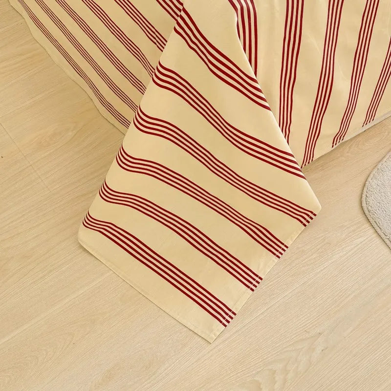 A close-up of beige and burgundy striped organic cotton bedding, showing a flat sheet and pillowcase.
