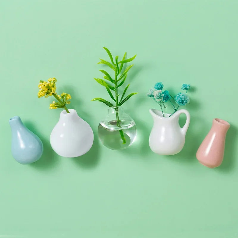 A collection of mini ceramic landscape fridge magnets featuring yellow and blue flowers in various white and pink glass vesse