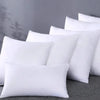 A stack of white breathable square core cushions resting on a gray surface.