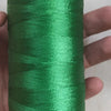 A hand holds a spool of bright green high tenacity polyester sewing thread with a yellow plastic base.