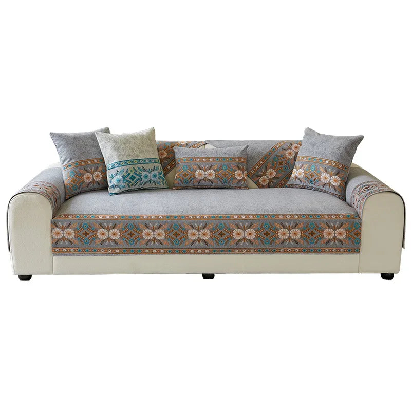 A beige sofa covered in patterned chenille fabric and decorated with various throw pillows.