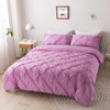 A pink quilted bedding set featuring a duvet and pillows on a bed in a bright room.