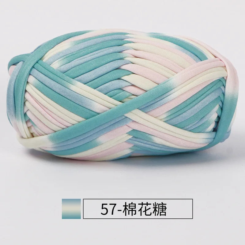 A ball of hand-dyed fabric strip yarn featuring shades of teal, pink, and white.