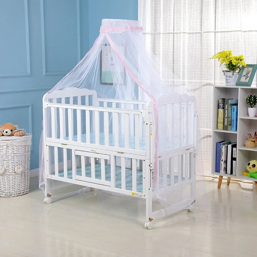 White crib mosquito net with sheer pink fabric draped over the sides