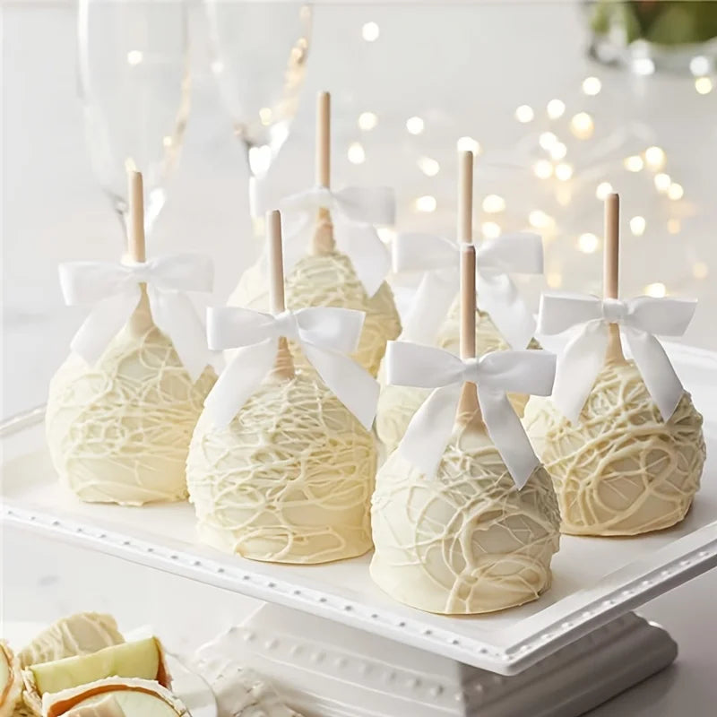 A display of white satin ribbon twist tie bows made of light-colored cake or fondant, arranged on a white platter.
