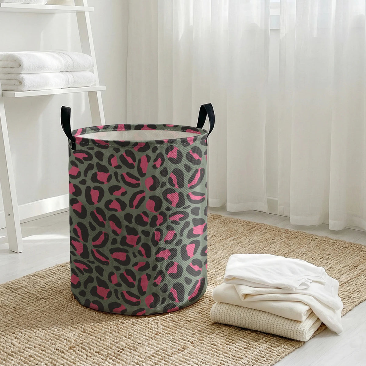 A foldable laundry basket with a leopard print design in shades of pink and green sits on a woven mat.