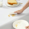 A hand is using a white cloth to wipe food residue from a plate on a table, demonstrating environmental protection.