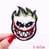 Embroidered skull iron-on patch featuring a fierce, grinning face with green flames and red accents.