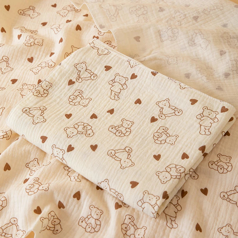 A soft double-layer cotton baby swaddle blanket with a subtle pattern lies on a light fabric background.