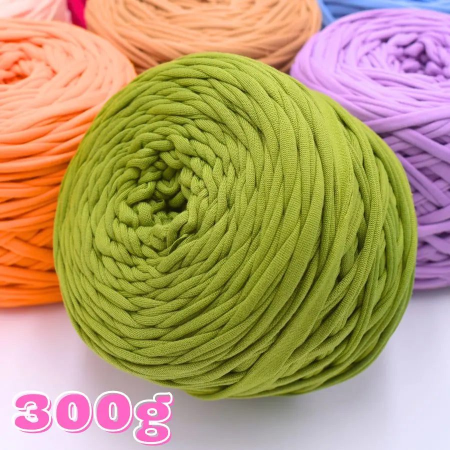 A ball of lime green craft yarn is shown next to spools of orange and purple yarns.