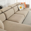 A beige jacquard elastic sofa cushion slipcover with an orange accent pillow on a light-colored sofa.