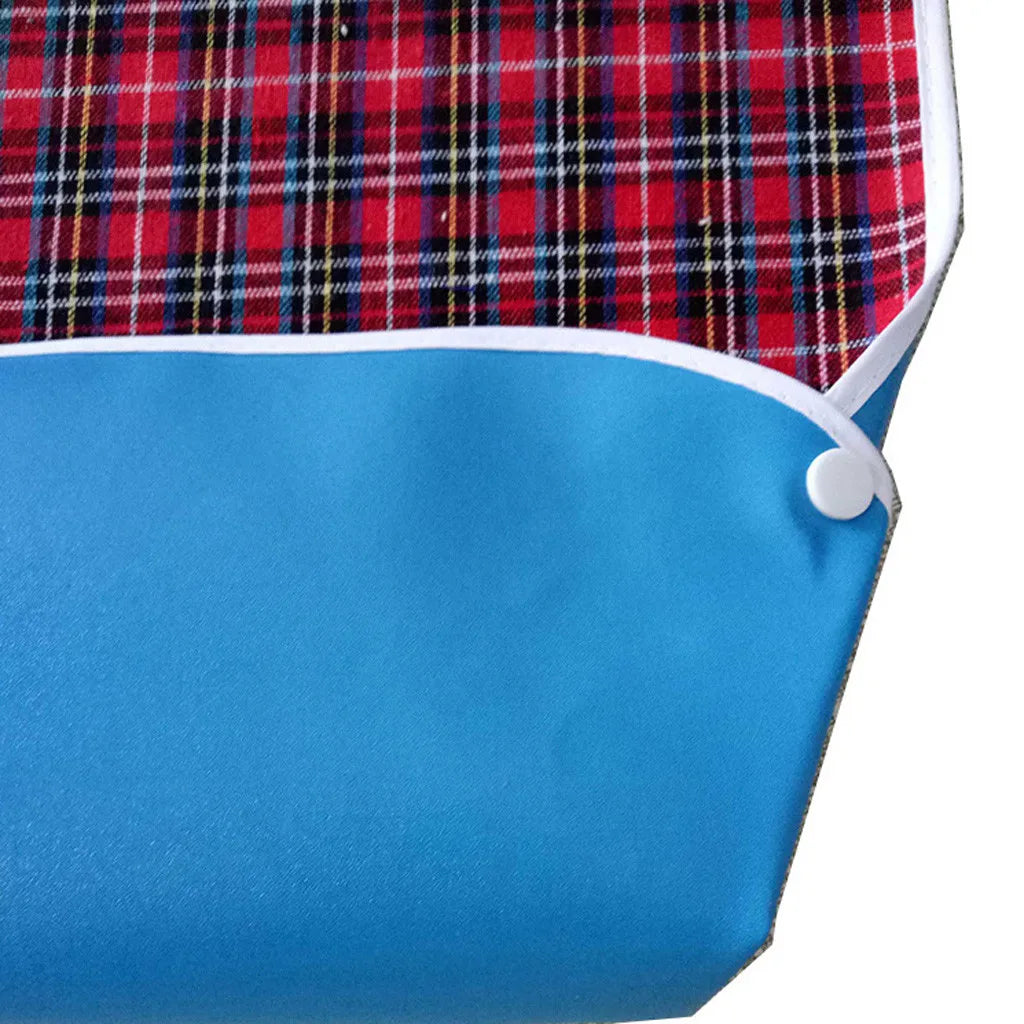 Blue waterproof mealtime bib with a red and black plaid fabric pattern.