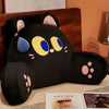 A black cat plush sofa cushion with yellow and blue eyes resting on a wooden surface.