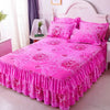 Pink fitted bed sheets with elastic lace trim displayed on a bed.