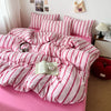 A pink duvet cover set with white stripes and matching pillowcases is displayed on a bed.