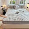 A luxury faux rabbit fur fitted sheet set displayed on a bed with light gray and white bedding.