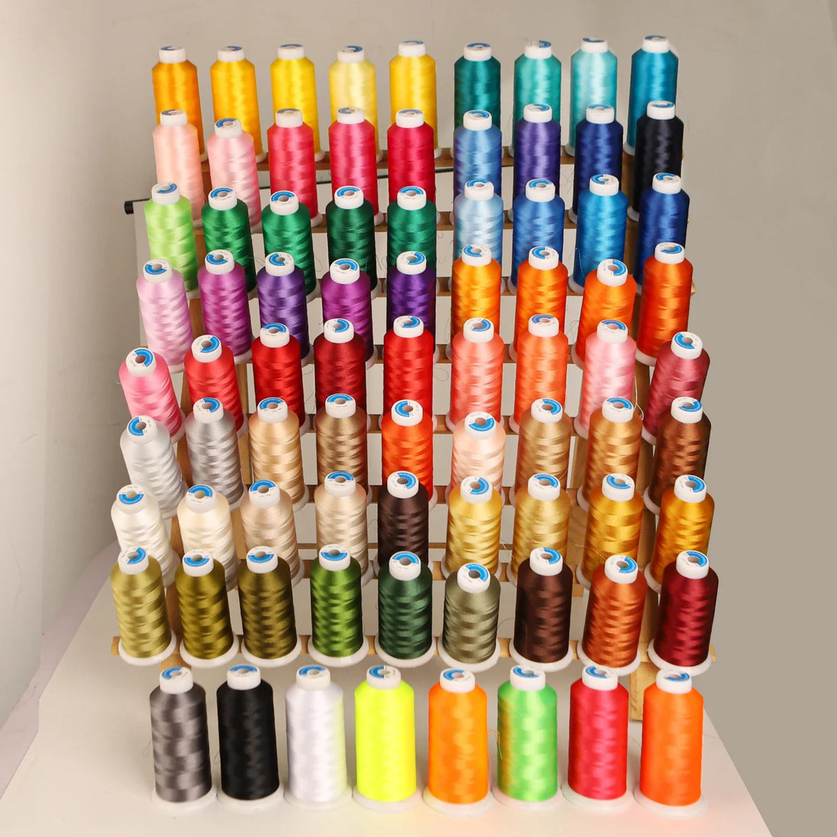 A vertical display of 80 colors of high tenacity machine embroidery thread in various shades and thicknesses.