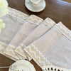 A stack of beige crochet macrame lace table runners resting on a wooden surface.