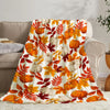 A patterned flannel throw blanket featuring autumn leaves and pumpkins in orange, yellow, and white tones.