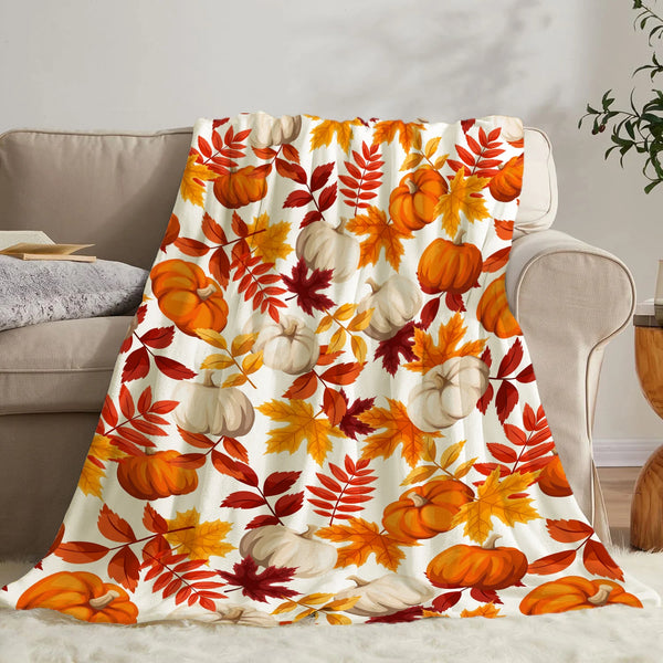 A patterned flannel throw blanket featuring autumn leaves and pumpkins in orange, yellow, and white tones.