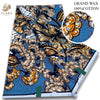 A bolt of grand wax print fabric featuring intricate orange and gold floral patterns on a blue background.