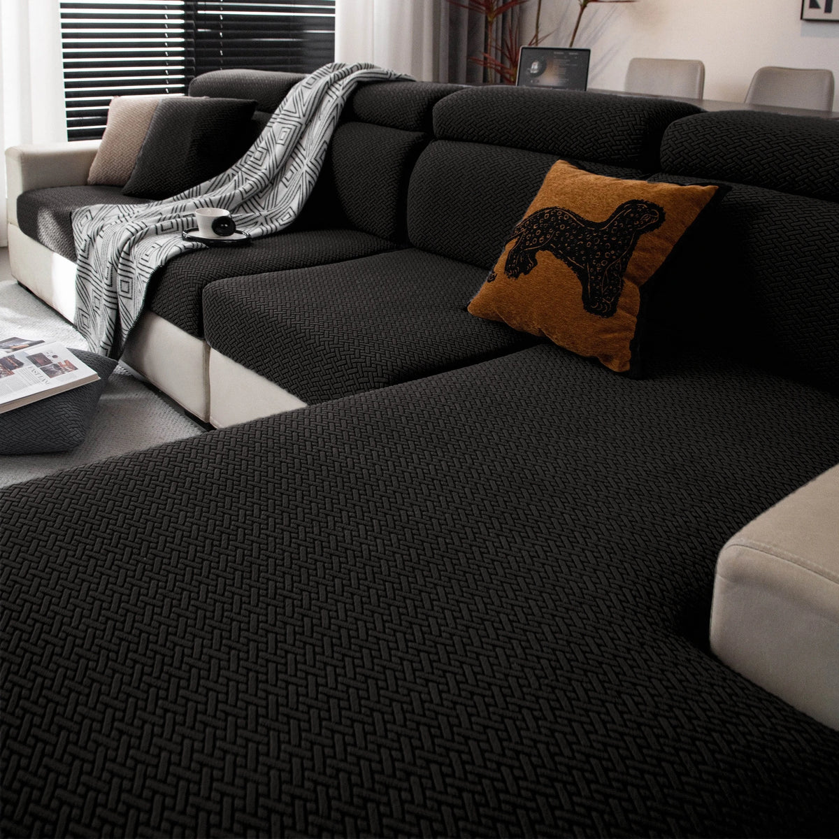 A dark gray stretchy polar fleece sofa cover with a textured weave and an orange throw pillow on a modern sofa.