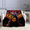 A black printed flannel travel blanket featuring a stylized superhero design with red, yellow, and blue accents.