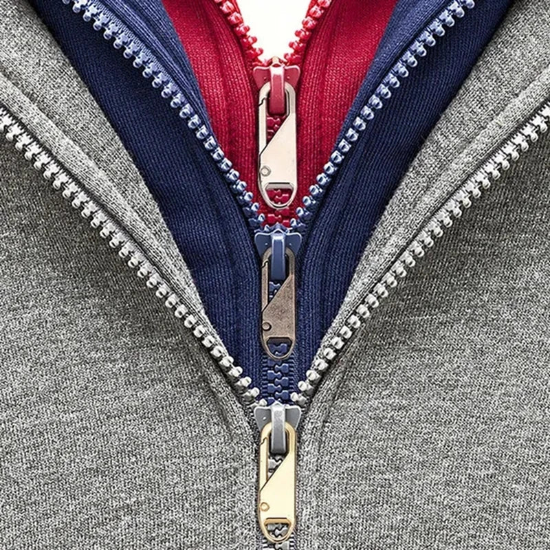 Close-up of a gray garment featuring a red and navy zipper with gold pull replacements.