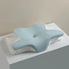 A light blue ergonomic memory foam cervical pillow resting on a white towel.