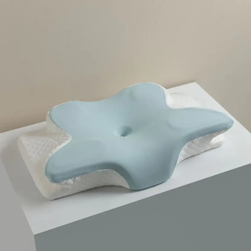 A light blue ergonomic memory foam cervical pillow resting on a white towel.