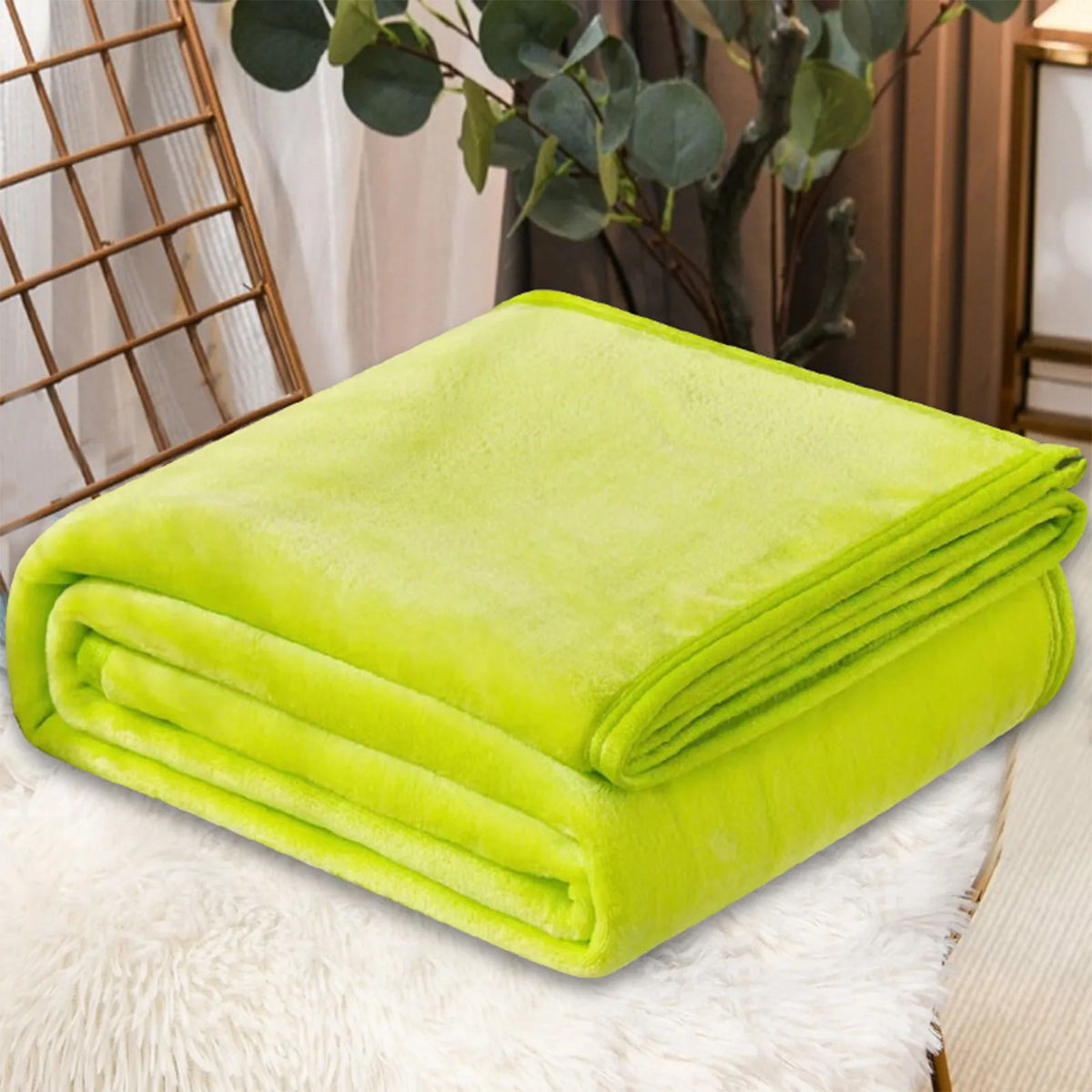 A bright lime green cozy coral fleece throw blanket folded neatly on a white fluffy surface.