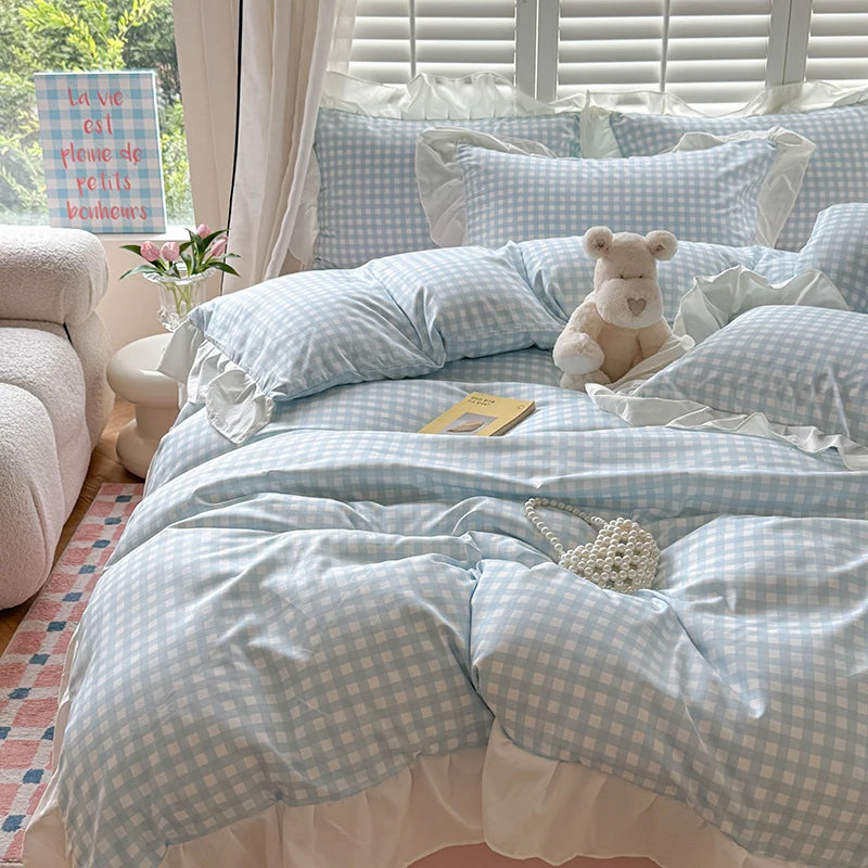 A light blue and white checkered duvet cover set with pillows and a teddy bear on a bed.