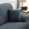 A close-up of a charcoal gray faux silk sofa cover with a dark cushion on a light-colored sofa.