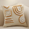 A cream-colored plush pillow cover featuring geometric patterns and a golden tassel detail.
