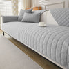 A light gray quilted anti-slip sofa cover with plush texture displayed on a modern sofa.