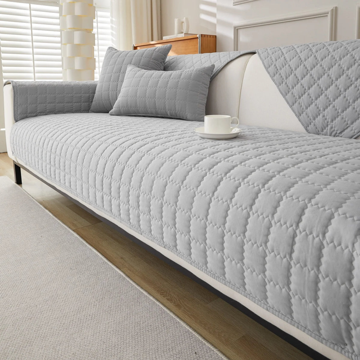 A light gray quilted anti-slip sofa cover with plush texture displayed on a modern sofa.