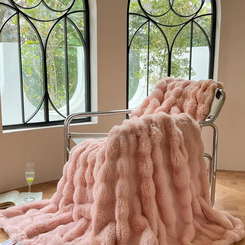 A fluffy pink faux fur throw blanket draped over a metal hanger in a bright room.