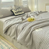 A light gray Korean style seersucker summer quilt set displayed on a bed with white and gray pillows.
