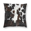 A square cushion cover made of faux fur cowhide print featuring black and white spots.