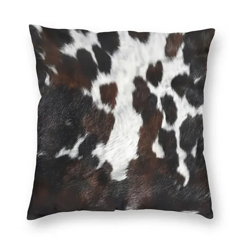 A square cushion cover made of faux fur cowhide print featuring black and white spots.