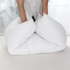 A white extra-long body pillow is shown with a person's hands resting on it, demonstrating its full-body support.