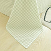A light green and white checkered fabric napkin or cloth laid on a wooden surface.