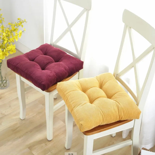A yellow tufted floor seat cushion resting on a white wooden chair frame.