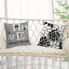 A gray square pillow with the text HOME SWEET HOME in black geometric print on a white woven chair.