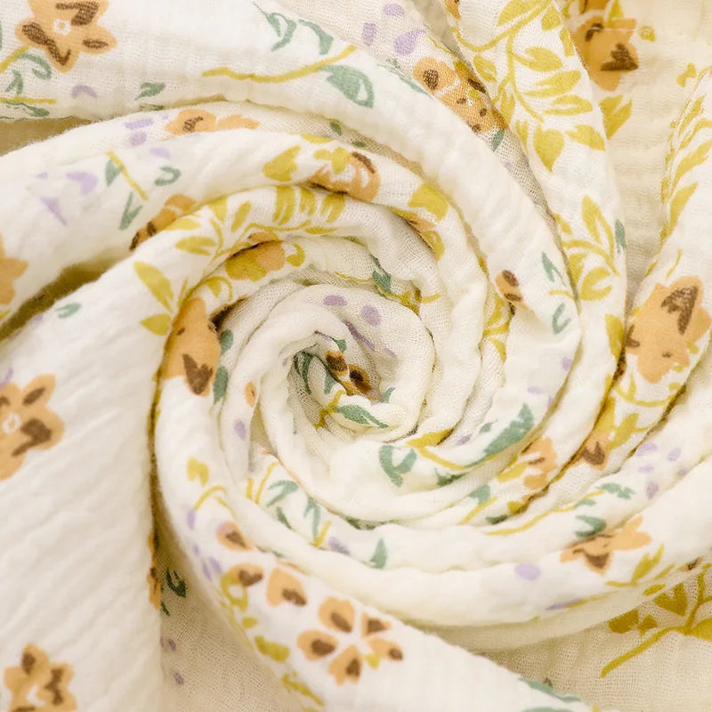 A rolled white and yellow patterned cotton crib sheet fabric.