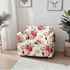 A floral patterned sofa cover featuring pink roses and green leaves displayed in a bright room.