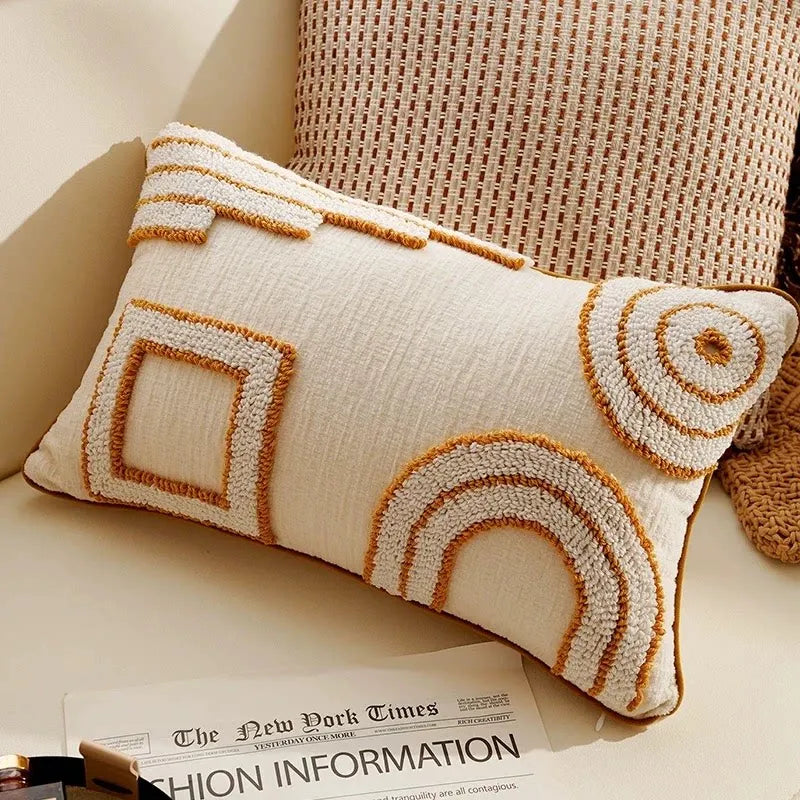A cream-colored knit pillow cover with geometric stitching in tan and beige tones resting on a newspaper.
