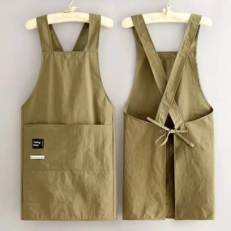 A khaki water-resistant kitchen apron with adjustable straps hanging on a wooden hanger.