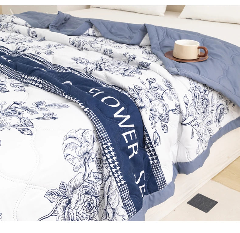 A white and blue floral duvet cover featuring detailed botanical illustrations on a bed.