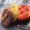Three tufted corduroy floor seat cushions in shades of yellow, orange, and brown resting on a gray fuzzy surface.